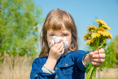 Child holding flower with pollen allergy symptoms