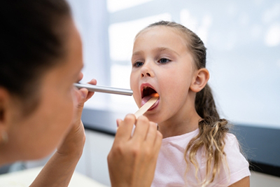 ENT doctor examining child's enlarged tonsils
